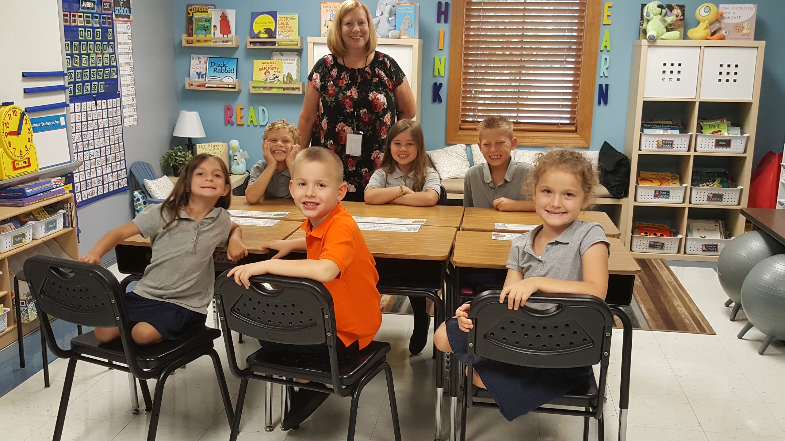 children around the table with female teacher in the background